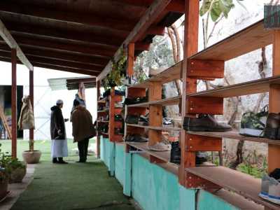 Nel cortile un grande capanno in legno protegge dalla pioggia gli uomini intenti a togliersi le scarpe su larghi tappeti azzurri che poi appoggiano su una lunga scarpiera in legno